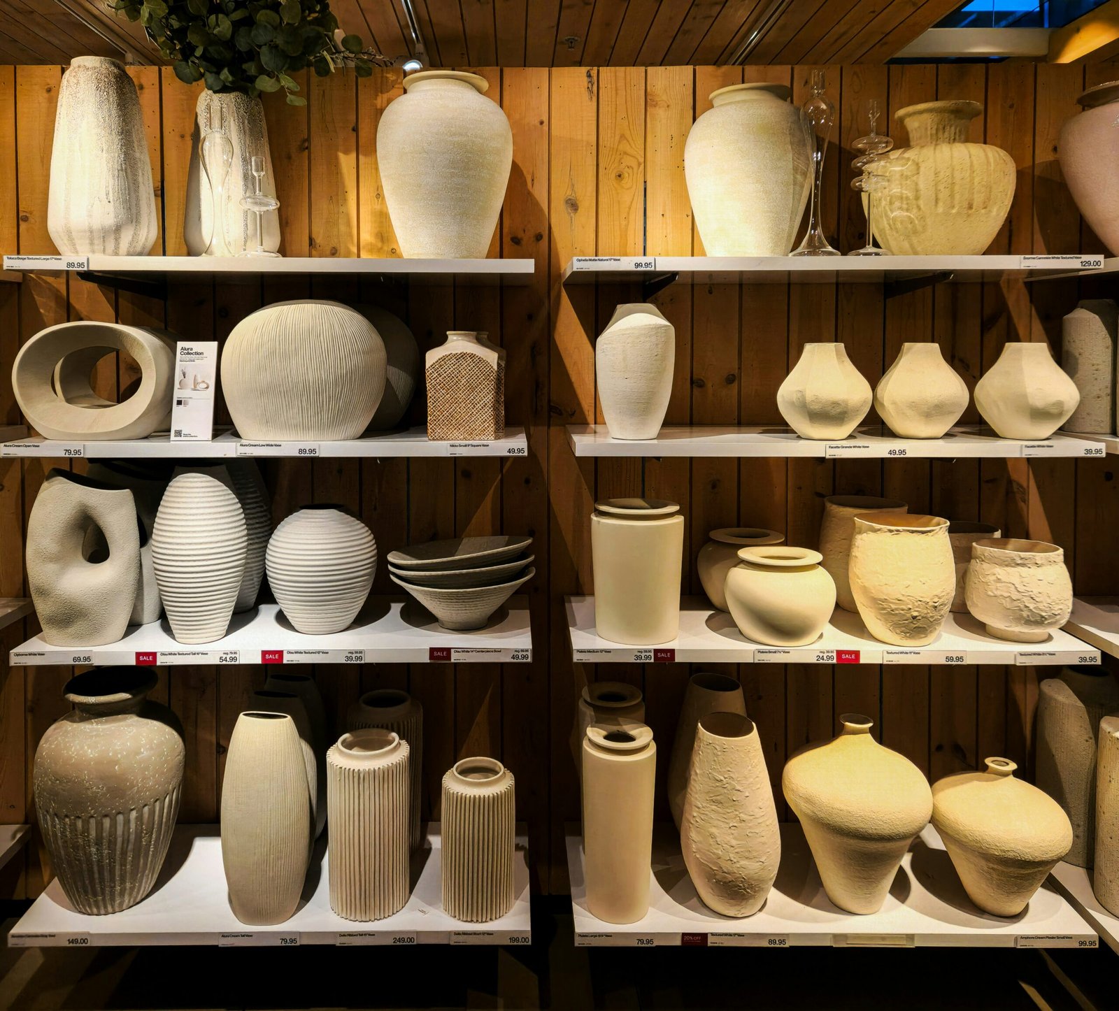 A shelf filled with lots of white vases